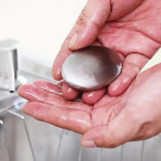 Stainless steel odor remover soap with black base placed near kitchen sink. Ideal for eliminating garlic, onion, and fish smells from hands.